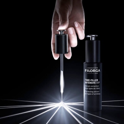 Frasco preto fosco de sérum FILORGA TIME-FILLER INTENSIVE 5XP com conta-gotas em fundo preto e luzes brancas