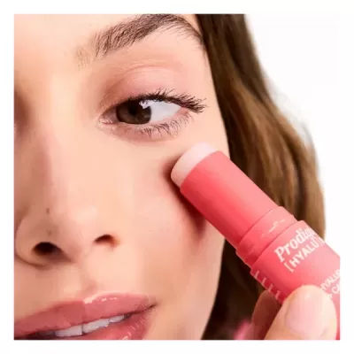 Mulher aplicando um produto facial em bastão cor coral na face