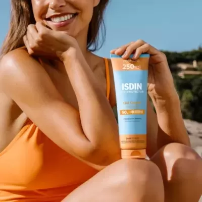 Mulher com fato de banho laranja segura tubo de protector solar ISDIN FPS 50+