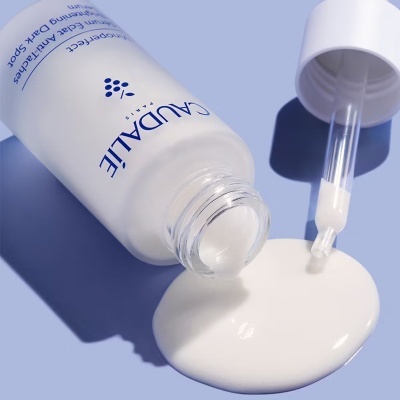 frasco branco CAUDALIE com líquido branco derramado e conta-gotas