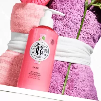 Loção corporal rosa Roger & Gallet perto de toalhas rosa e roxa com faixa branca