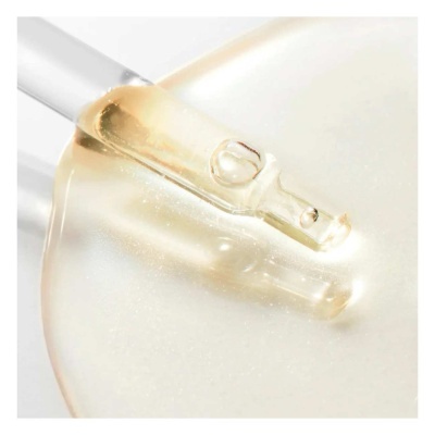 Conta-gotas de vidro com líquido dourado sobre superfície creme