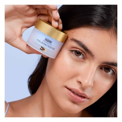 Frasco do creme ISDIN Hyaluronic Moisture com tampa dourada junto ao rosto de mulher com pele clara
