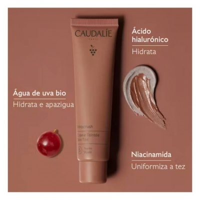 Tubo de creme bronzeador CAUDALIE Vinocrush e uva vermelha sobre fundo castanho