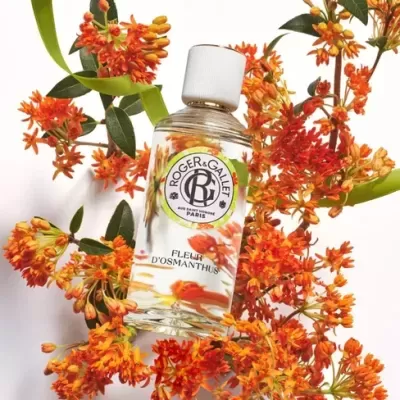 Frasco de perfume Roger & Gallet rodeado por flores laranja e folhas verdes