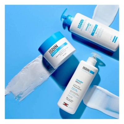 Três produtos ISDIN para cuidados da pele em fundo azul com creme branco