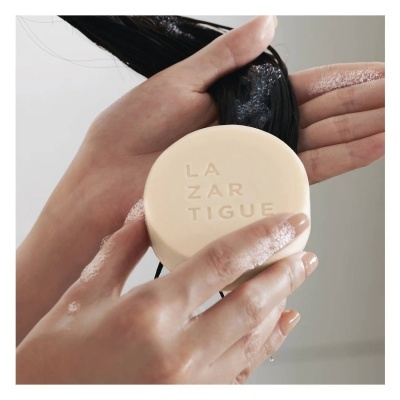 Mãos a usar barra de sabão LAZARTIGUE no cabelo molhado e ensaboado