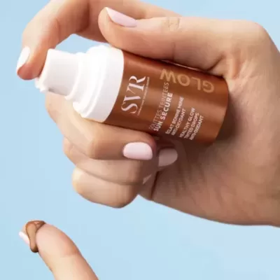 Frasco doseador cosmético castanho e branco com produto aplicado no dedo