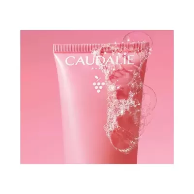Tubo rosa do produto CAUDALIE PARIS com bolhas de sabão sobre fundo rosa.