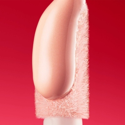 Produto cosmético rosa claro numa escova com cerdas rosadas densas