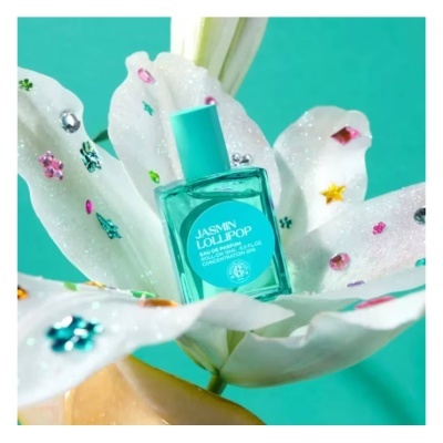 Frasco de perfume azul turquesa sobre flor branca com brilhantes coloridos.