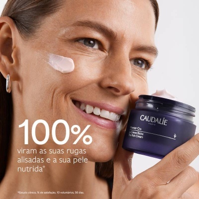 Mulher a aplicar creme Caudalie no rosto, segurando pote roxo da marca