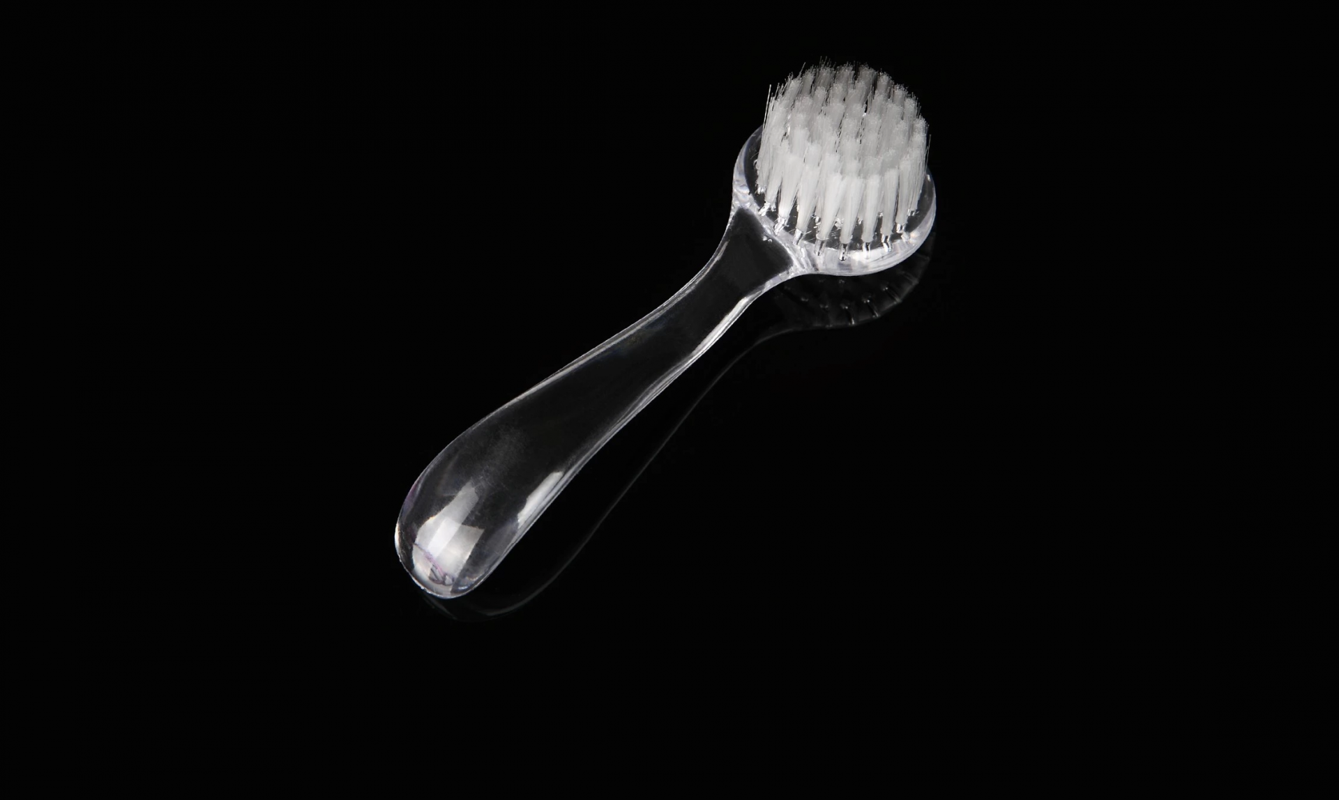 ESCOVA DE LIMPEZA Escova facial transparente com cerdas brancas sobre fundo preto.