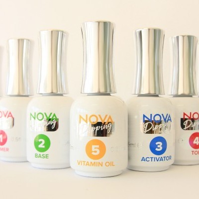 Sete frascos de tratamento para unhas NOVA, com tampas prateadas, numerados de 1 a 5, sobre fundo branco.