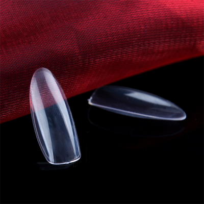 Protetores de unhas transparentes em fundo preto com tecido vermelho atrás.