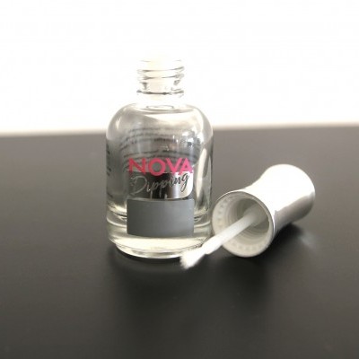 Frasco de vidro transparente com pincel aberto em superfície preta