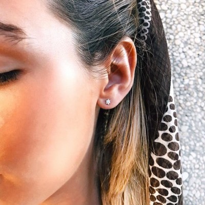 Brinco pequeno de prata em forma de flor com pedra brilhante em orelha