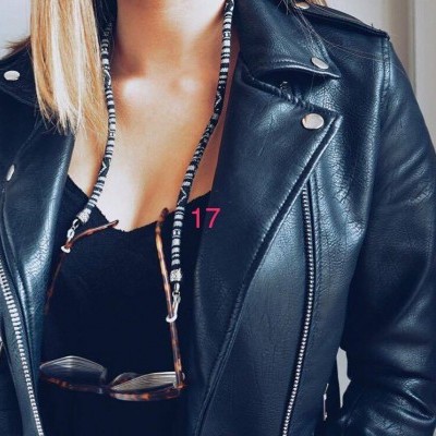 Jaqueta preta de pele com óculos pendurados por fio preto e branco e o número 17 em rosa visível