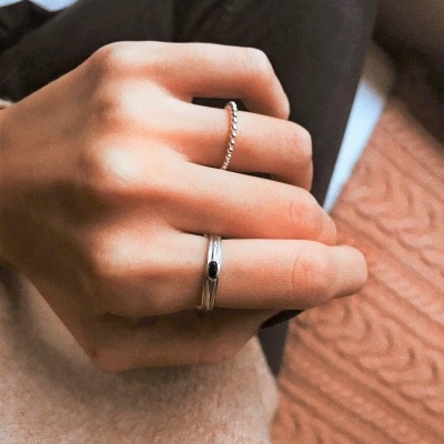 Mão com dois anéis prateados, um com pedra preta e outro com padrão em bolinhas