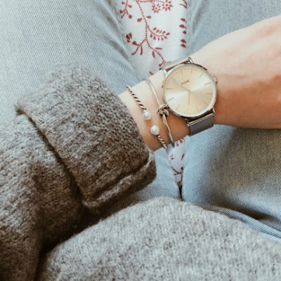 Relógio de pulso prateado com pulseiras e roupa cinzenta