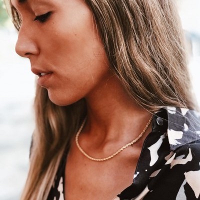 Colar dourado fino com corrente tipo cordão usado por mulher