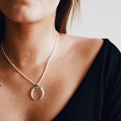 colar prateado com pendente meia-lua numa mulher com blusa preta