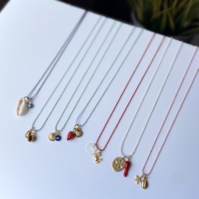 Sete colares coloridos com pendentes variados sobre fundo branco