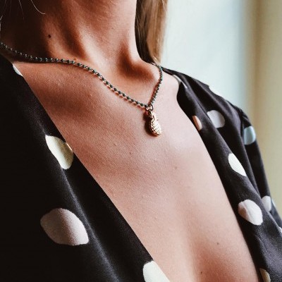 Colar com pendente de abacaxi e vestido preto às bolinhas