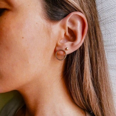 Mulher com brincos dourados em forma de estrela e círculo na orelha direita