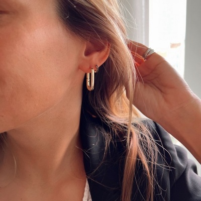 Brincos dourados em orelha feminina com cabelo loiro