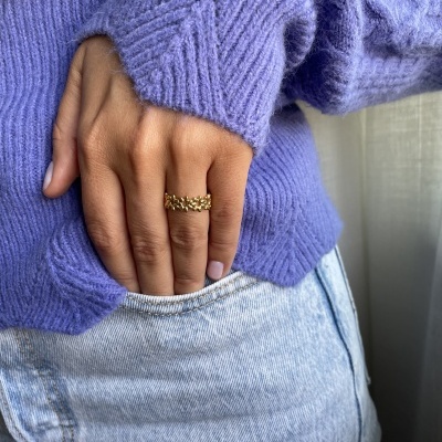 Anel dourado na mão direita com sweater roxo e calças de ganga azul claro