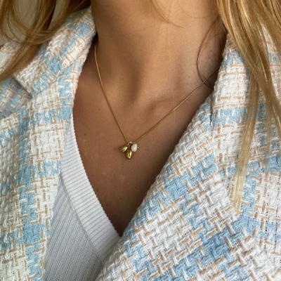 Colar dourado com pendentes usados com casaco azul claro texturado