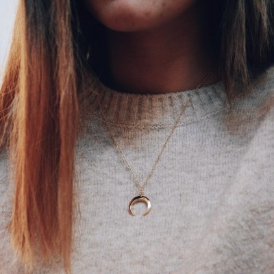 Colar dourado com pendente meia-lua e camisola cinzenta