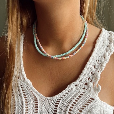 Colar de contas azul claro e multicolorido usado com camisola branca de malha