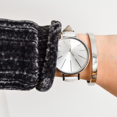 Relógio de pulso prateado com bracelete branca e pulseira metálica no pulso