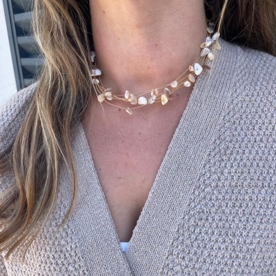 Colar delicado com pedras brancas e bege usado com cardigan bege texturizado