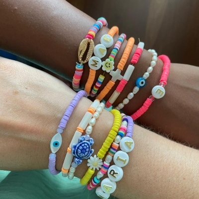 Pulseiras coloridas de contas e pérolas com símbolos e letras nos pulsos de duas pessoas