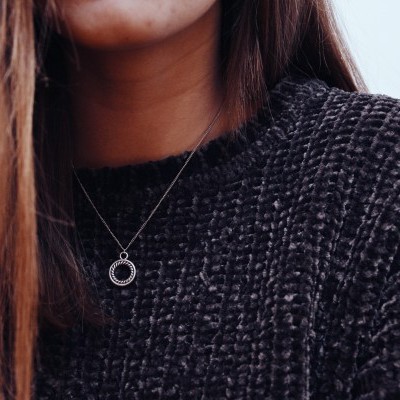 Colar com pendente circular prateado usado com camisola preta