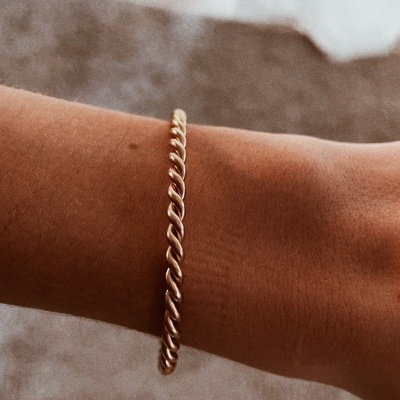 Pulseira dourada torcida no pulso de uma pessoa