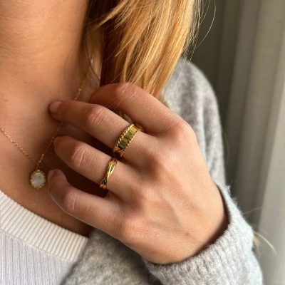 Mão feminina com duas alianças douradas e pendente com pedra branca