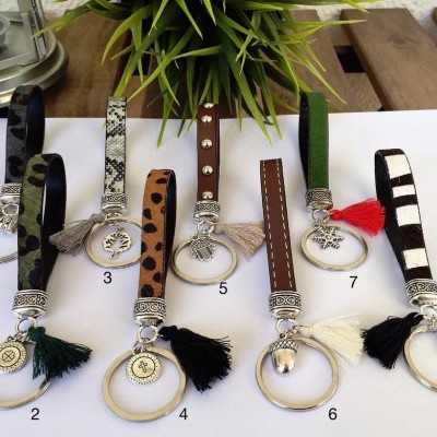 Oito porta-chaves variados com diferentes padrões, argolas douradas e pompons coloridos