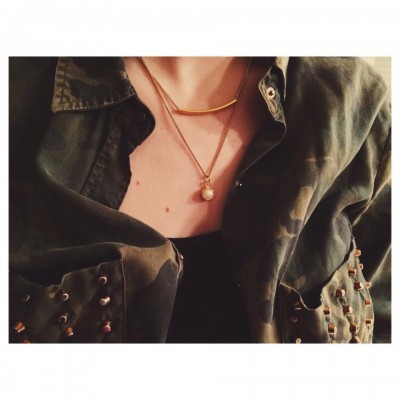 Pessoa vestindo camisa camuflada verde com tachas e colares dourados