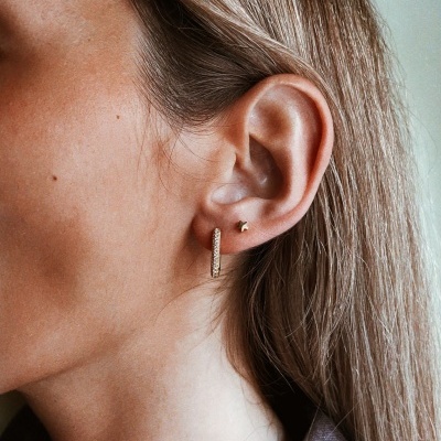 Brincos dourados no ouvido de mulher com cabelo loiro