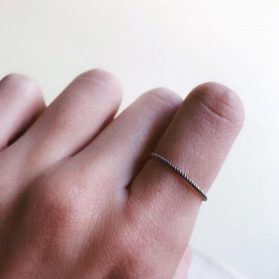 Mão com anel fino de metal prateado no dedo médio