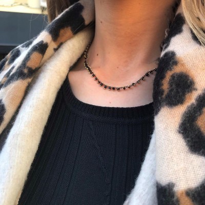 Colar delicado com esferas negras e douradas e camisola preta com cachecol de padrão leopardo.