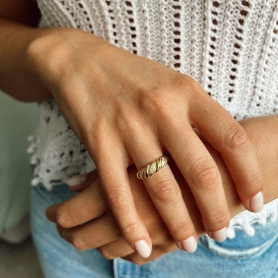 Anel dourado trançado no dedo anelar de mão feminina