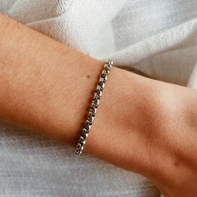 Pulseira de metal prateado com elos grossos no braço