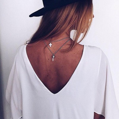 Blusa branca com decote V profundo nas costas e colares prateados