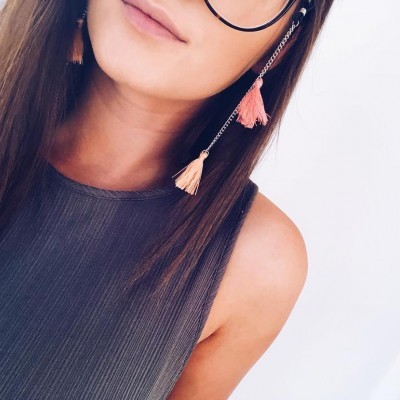 Mulher jovem com óculos e blusa cinza canelada em fundo branco