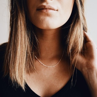 Colar delicado em metal prateado usado por mulher com camisola preta